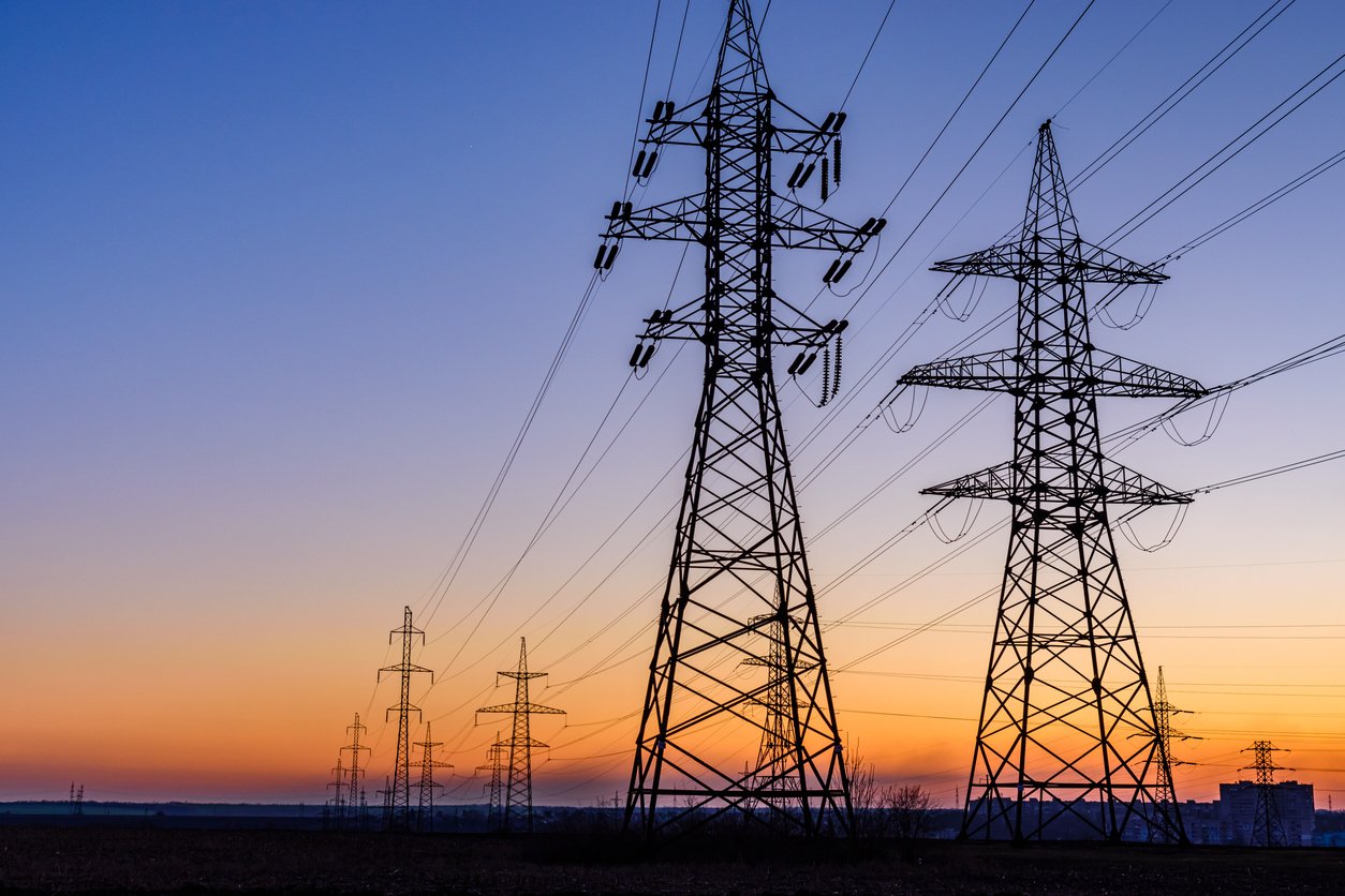 High voltage power line in a field at sunset