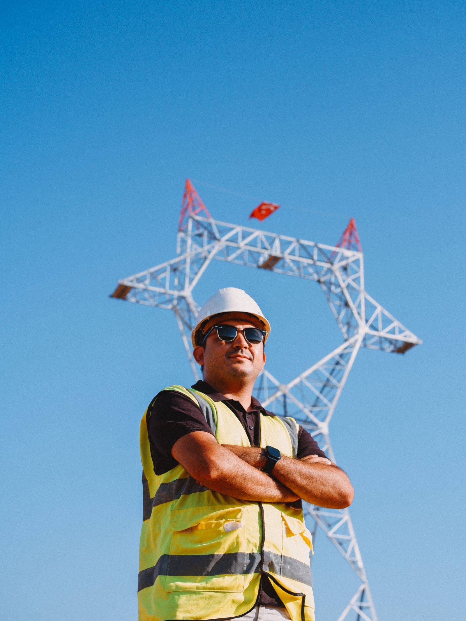 confident engineer poses near transmission tower